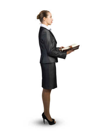 A businesswoman in a business suit stands with an open diary in her hands. On a white backgroundの写真素材