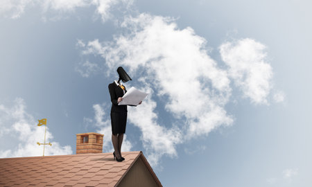 Faceless businesswoman with camera zoom instead of head standing on house roofの写真素材