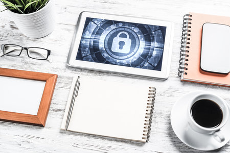Business workplace with office stuff and tablet with padlock icons on screenの写真素材