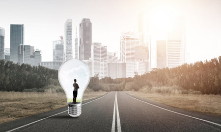 Young businesswoman trapped inside of light bulb on asphalt roadの写真素材