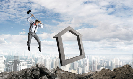 Jumping businessman crashing big house symbol with city view on background. 3D rendering.の写真素材