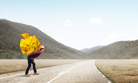 Builder man carrying paper ball on his backの写真素材
