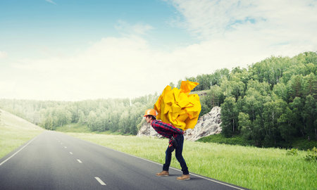 Builder man carrying paper ball on his backの写真素材