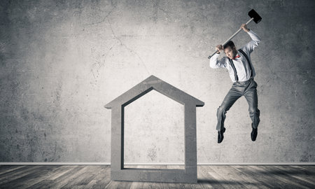 Determined businessman going to break with hammer house concrete figureの写真素材