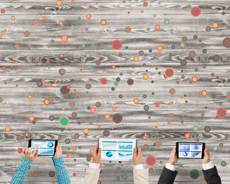 Group of three people with devices in hands working together as symbol of networking and communicationの写真素材