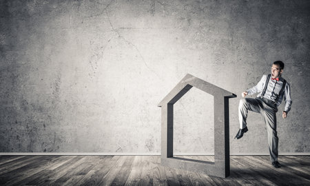Determined businessman going to break with kick house concrete figureの写真素材
