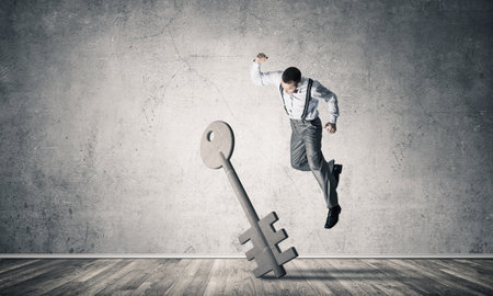 Determined businessman in empty interior breaking with fist stone key figureの写真素材