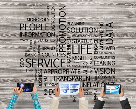 Group of three people with devices in hands working together as symbol of networking and communicationの写真素材