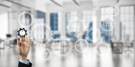 Close of businesswoman hand touching gears on screen with finger and office at backgroundの写真素材