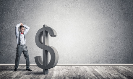 Young furious businessman going to crash with hands stone dollar symbolの写真素材