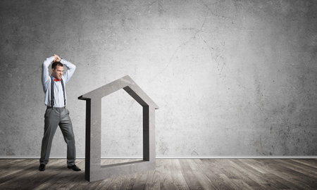 Determined businessman going to break with hands house concrete figureの写真素材