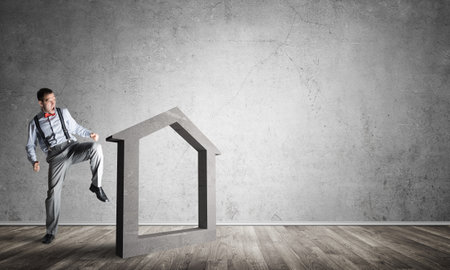 Determined businessman going to break with kick house concrete figureの写真素材