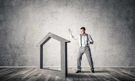 Determined businessman going to break with fist house concrete figureの写真素材