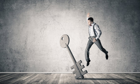 Determined businessman in empty interior breaking with fist stone key figureの写真素材