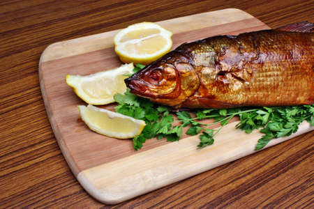 Fish smoked whitefish on a chopping board with lemon and parsleyの写真素材