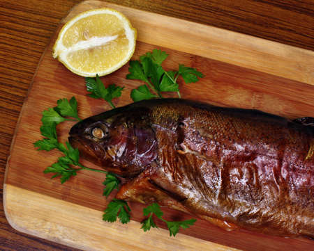Fish smoked trout on a chopping board with lemon and parsleyの写真素材
