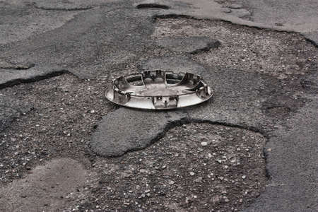 Wheel cover clipped on the damaged road with holesの写真素材