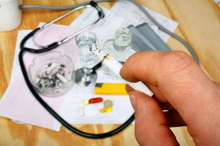Burning cigarette held by the patient smoker against the results of medical research