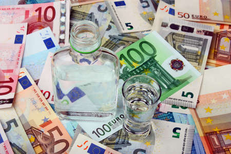 Bottle and a glass of vodka on a background euro moneyの写真素材
