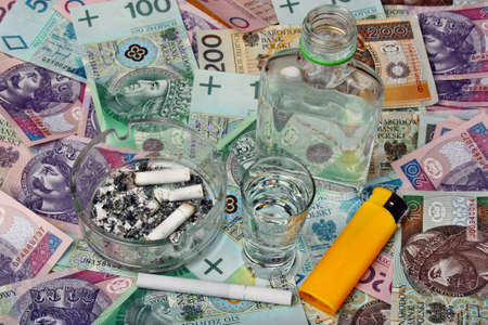 Cigarettes, bottle and a glass of vodka on a background polish moneyの写真素材