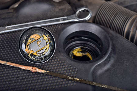 The thick, greasy yellow motor oil under oil cap as signs and symptom of a blown head gasket. Broken a carの写真素材