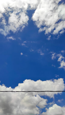 The view of white clouds with a bright blue sky behind the leaves and trees in the Cikancung area,...