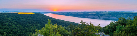 A magnificent panorama of a wide river flowing between the green beaches. With yellow squares of...