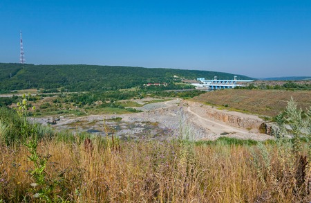 Rocky rock cavity on the background of a river cleaning dam and green mountainsの写真素材