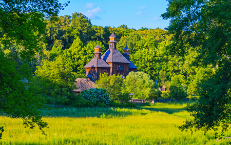Beautiful wooden church on a background of green trees and blue skyの写真素材