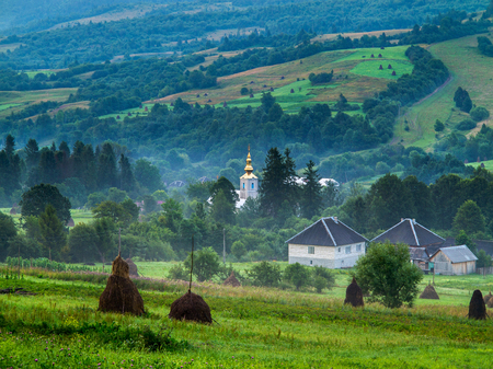 descent through the hayloaf with logs on a slope from the valley to the village in the fogの写真素材