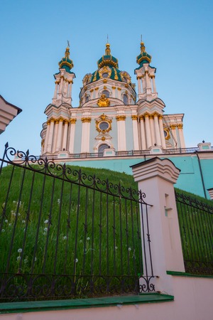 A tall temple with golden domes surrounded by a fence made of wrought ironの写真素材