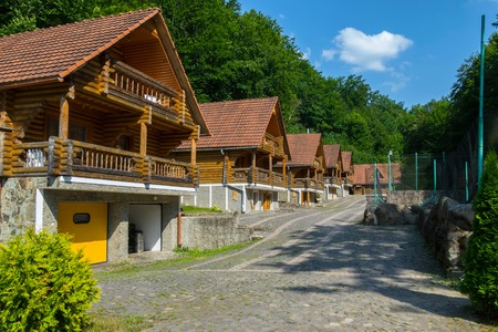 a series of wooden cottages on a recreation center near a green mountain in the Carpathiansの写真素材