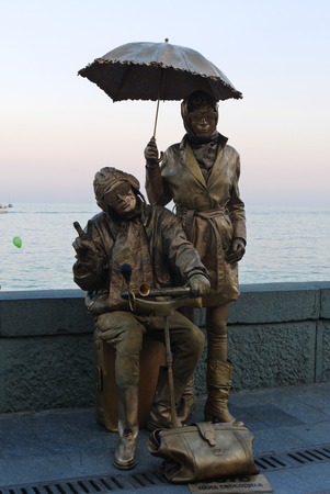 Brass monument to a man and a woman with an umbrella, in tank helmets and glassesの写真素材