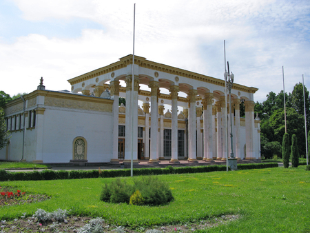 building with white columns and walls with a pattern on a green lawn in the parkの写真素材