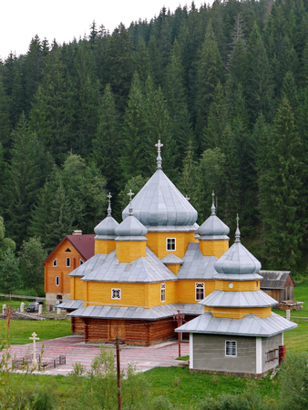 neat and well-groomed church with domes on the background of a dense green forestの写真素材