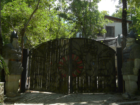 two fabulous heroes are guarded by huge wooden gates with a forged fantasy pattern leading to a large white modern house in the forest. place of rest and travelの写真素材