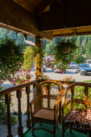 Comfortable wooden veranda with wicker chairs on the background of car parkingのeditorial素材