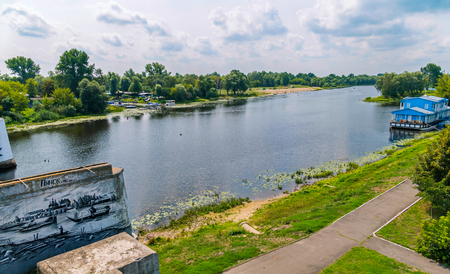 Beautiful scenery of the river on a cloudy summer day with beaches on the opposite shore with a parking lot for boats and green vegetation pleasing to the eye.の写真素材