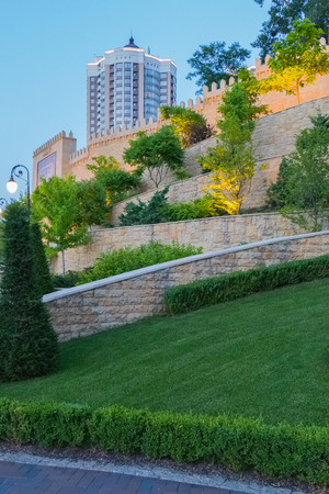 Beautiful decorative trees and neatly trimmed green lawn on the background of a large wall with an ornamental carpet imageの写真素材