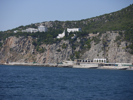 Stone coast of blue, deep sea with green trees and bushesの写真素材