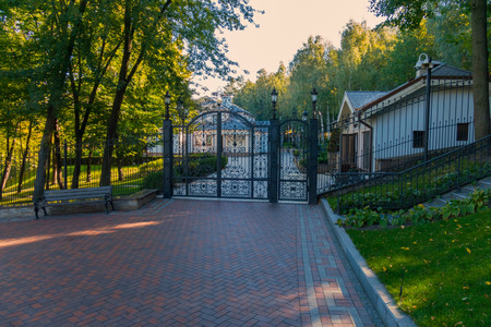Entrance to the territory closed with an iron gate with a door made of their figured lattices with...