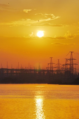 yellow sunset over the water against a power plant backgroundの写真素材
