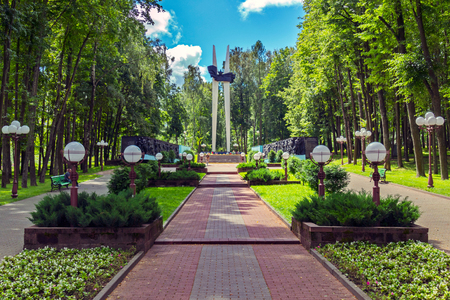a track with plantings of bushes and lanterns by bullets on the sides, leads to the monument of the memorialの写真素材