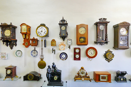 A collection of antique watches of various shapes and sizes placed on a white wall in the museum's premises.のeditorial素材