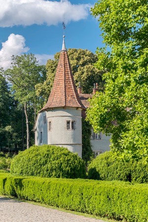 A low tower of the castle with a red roof and slit against the background of green trees and blue skyのeditorial素材