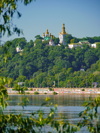A picturesque view of the golden domes of church temples on the background of the city embankmentの写真素材