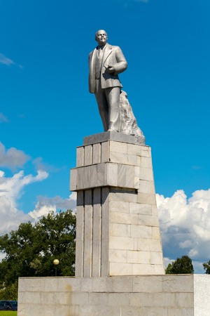 The monument of the historical person V.I. Lenin standing on a high pedestal against the blue sky. One of the most common monuments on the teritory of the former USSR.のeditorial素材