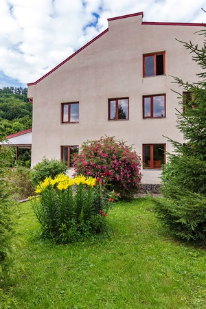 Beautiful scenery from the window the tenants see the house in the photo. Greenery, a flower bed with yellow and red flowersの写真素材