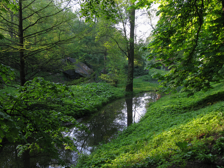 A tiny river between the green slopes covered with grassの写真素材