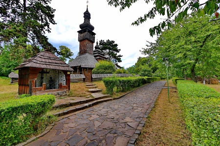 The path in the historic park is located near an ancient chapel with wooden walls and a satraja church also made of wood with blackened by time walls and a dome.の写真素材